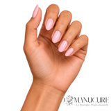 Manucure rose pastel poudré 1944 Paris Aurélia sur ongles amande brillants et main à peau mate.