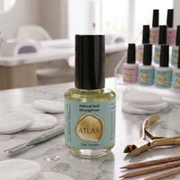 Flacon de Natural Nail Strengthener ATLAS 15ml, présenté dans un environnement professionnel d'onglerie sur une table en marbre.