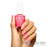 Main tenant le flacon de vernis semi-permanent OPI GelColor If U Like Pinka Coladas, affichant une manucure rose scintillante sans HEMA ni TPO.
